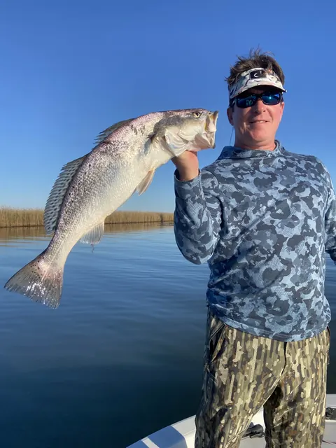 Angler in a visor holding up his catch over calm water near Venice, Louisiana
