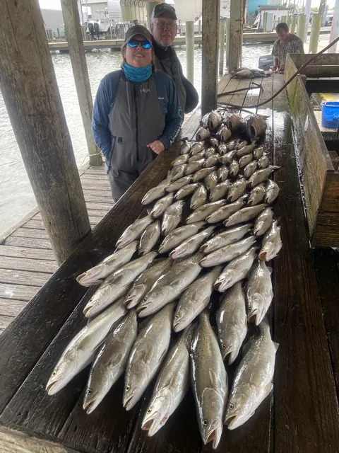 Two anglers beside rows of speckled trout on the cleaning dock in Venice, Louisiana