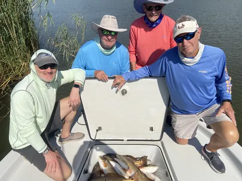 Four anglers gathered around a fish box of redfish on the boat near Venice, Louisiana