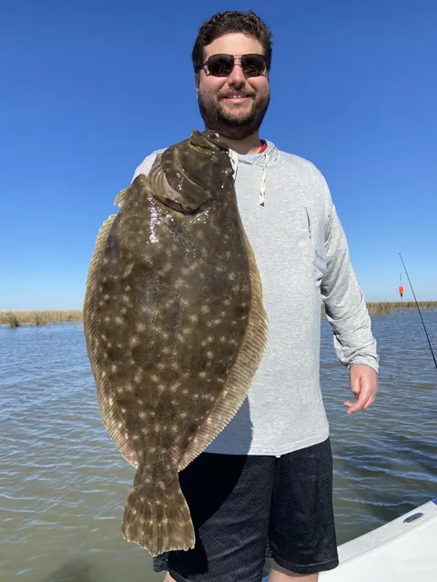 Angler holding up a large flounder under a blue sky near Venice, Louisiana