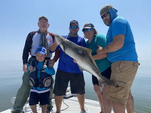 A group on the boat, with a young angler in front, holding up a large fish near Venice, Louisiana