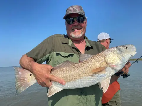 Angler in a green shirt cradling a large redfish near Venice, Louisiana