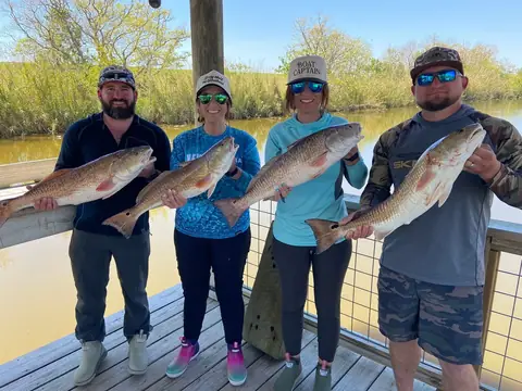 Four anglers each holding a redfish on the dock in Venice, Louisiana