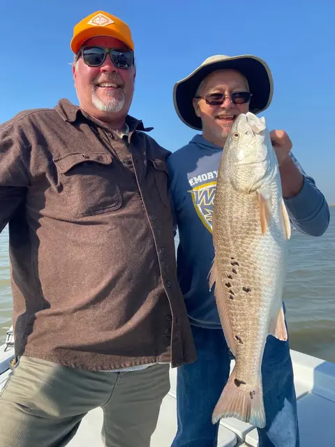 Two anglers on the bow holding a redfish upright near Venice, Louisiana