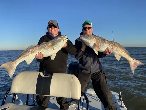 Two anglers on the boat each holding a redfish near Venice, Louisiana