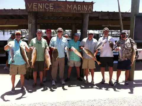 Group of anglers holding redfish under the Venice Marina sign